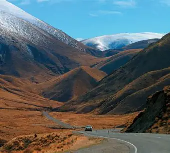 The Lindis Pass road winding through golden tussock high country, Central Otago, New Zealand